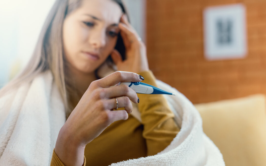 Woman sick with the flu staring at the thermometer because she does not have a fever.